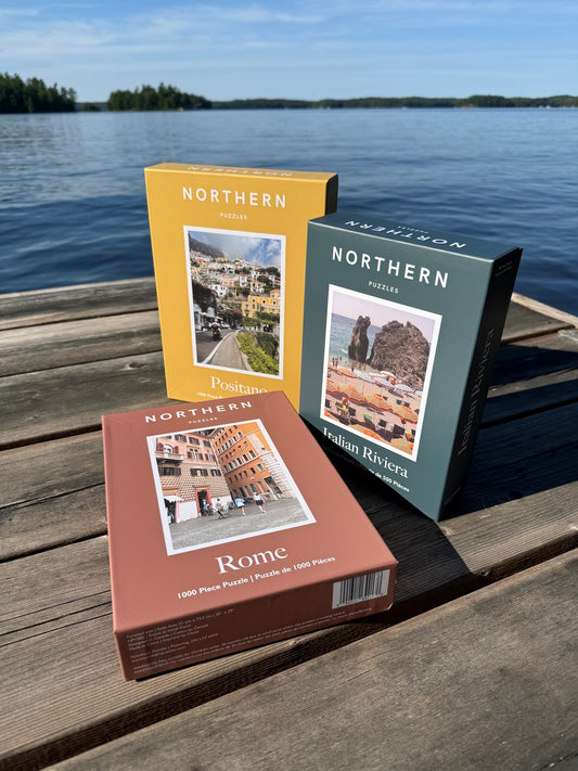 Three travel-themed books on a wooden dock by a lake