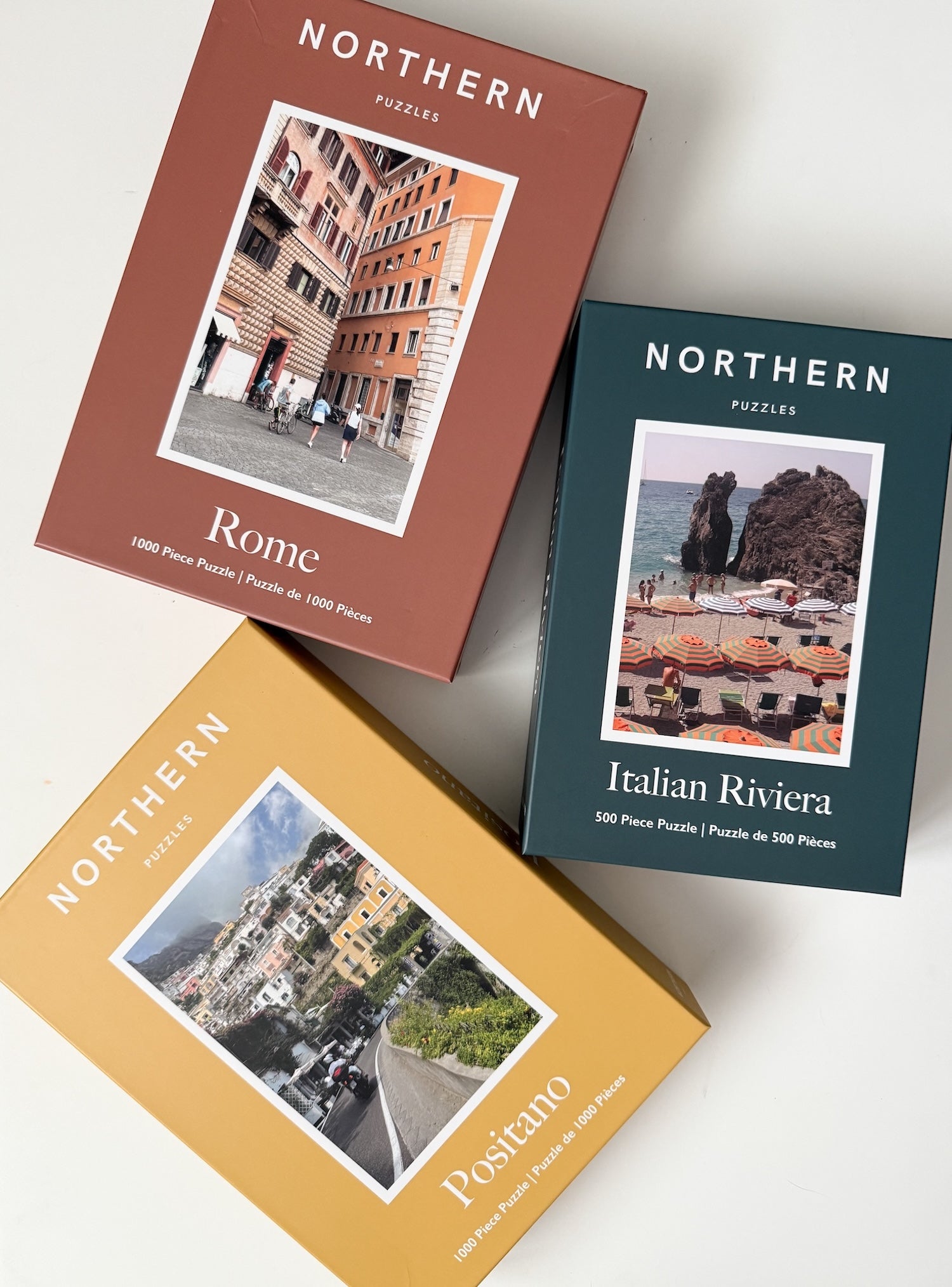 Three 'Northern Puzzles' boxes featuring images of Rome, Italian Riviera, and Positano on a white background.